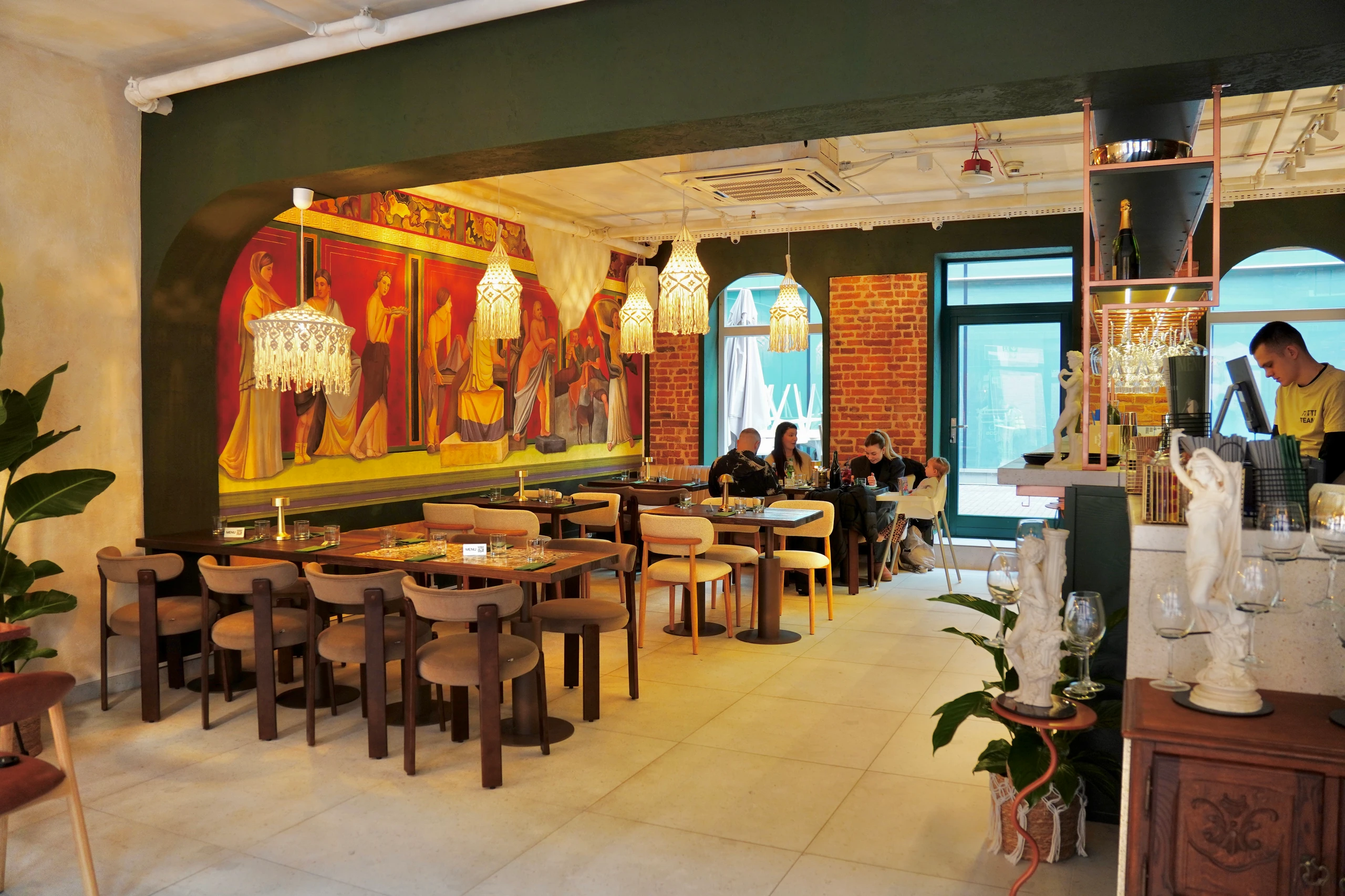 Wnętrze restauracji Tutti w Krakowie z muralem inspirowanym włoskimi freskami.